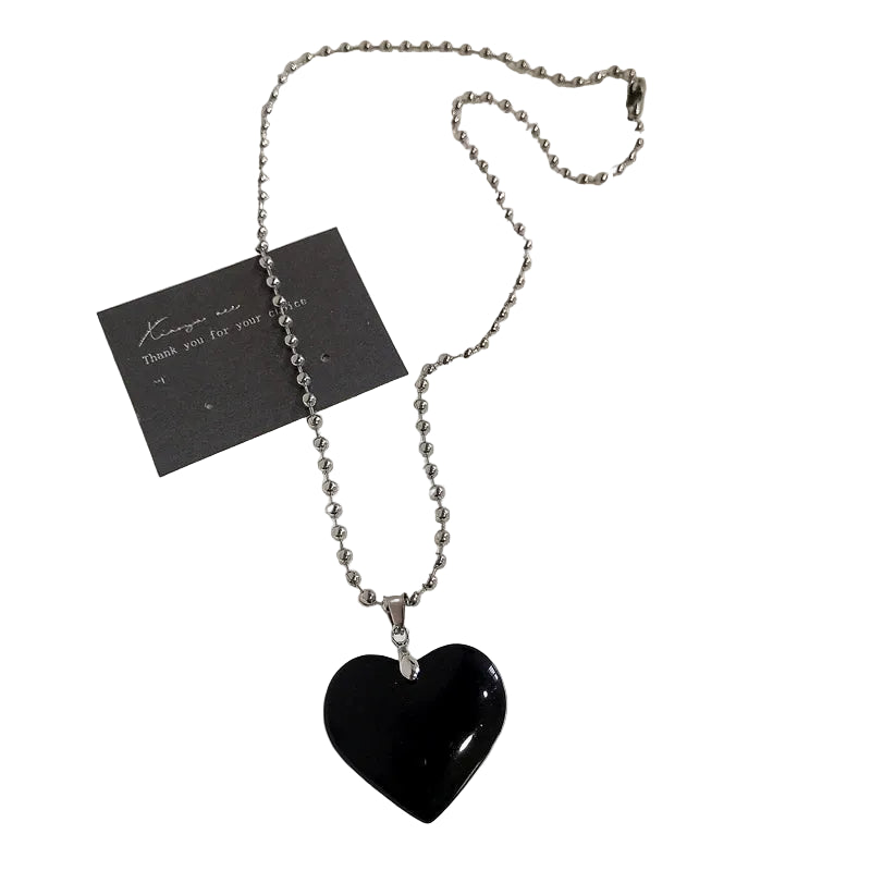 Black heart-shaped pendant on a beaded chain with a card on a white background